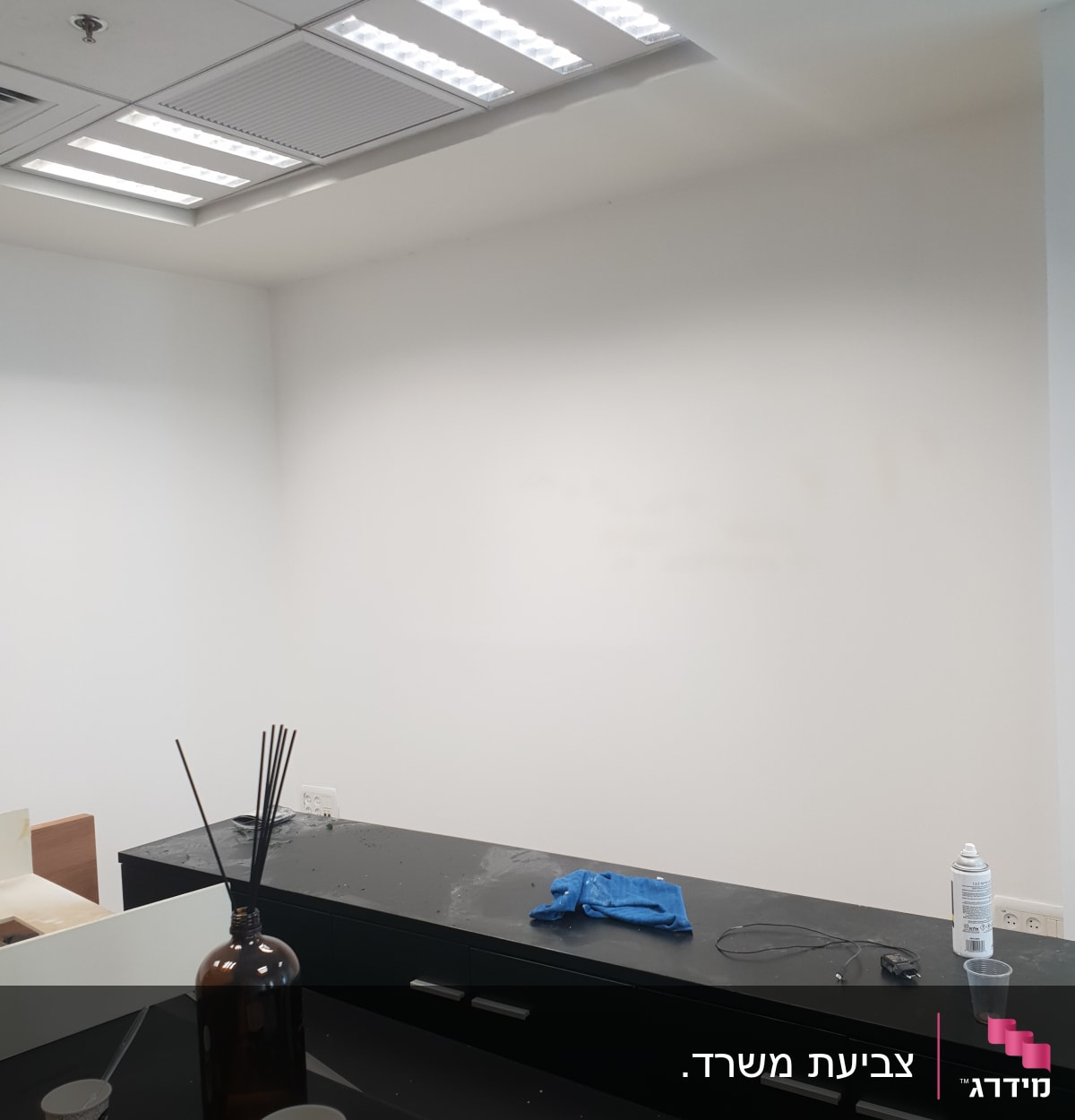 קיר לבן עם פחית צבע וכפפה על שולחן